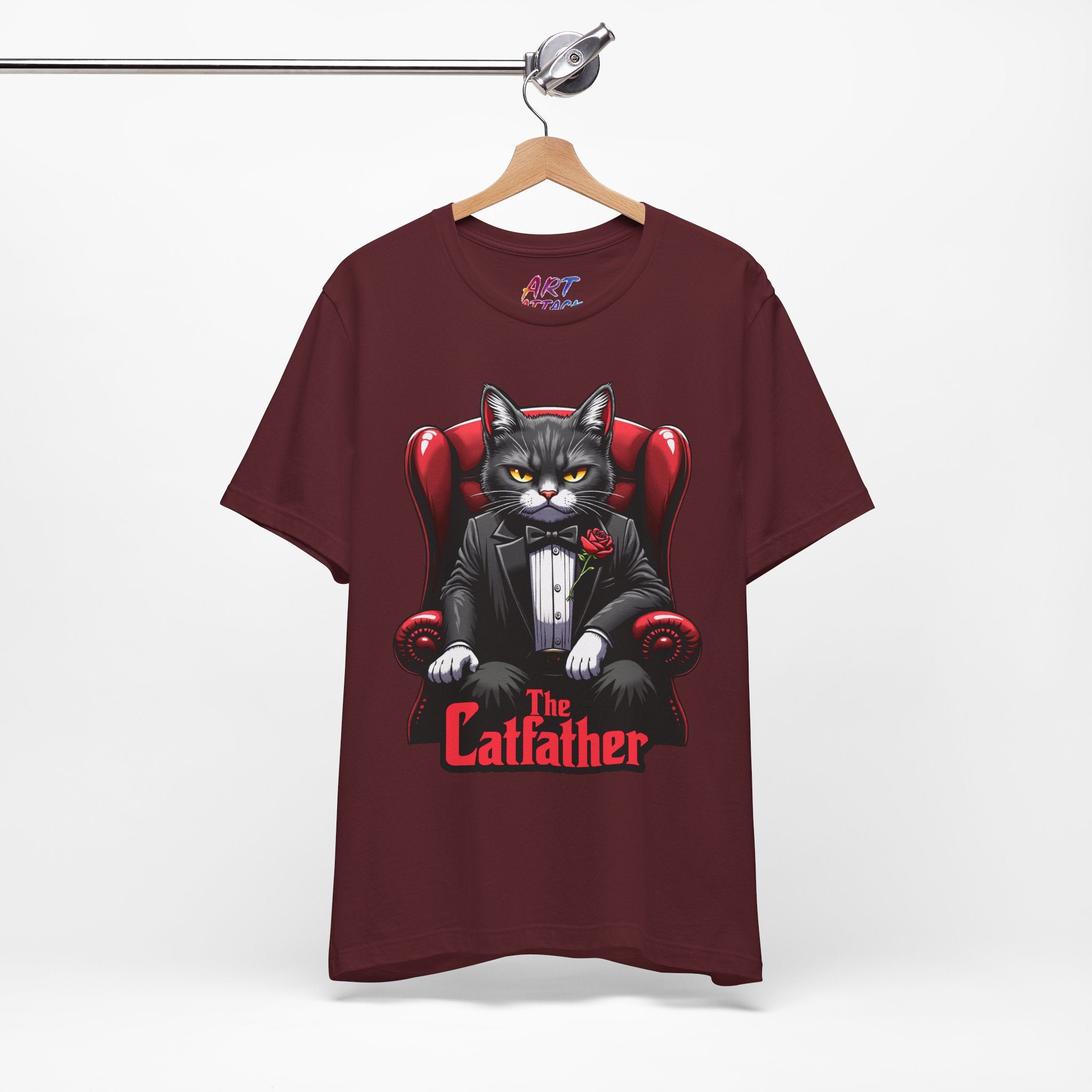A serious grey cat dressed in a black tuxedo with a red rose on the lapel, sitting like a mafia boss in a red leather armchair with the text The Catfather below.