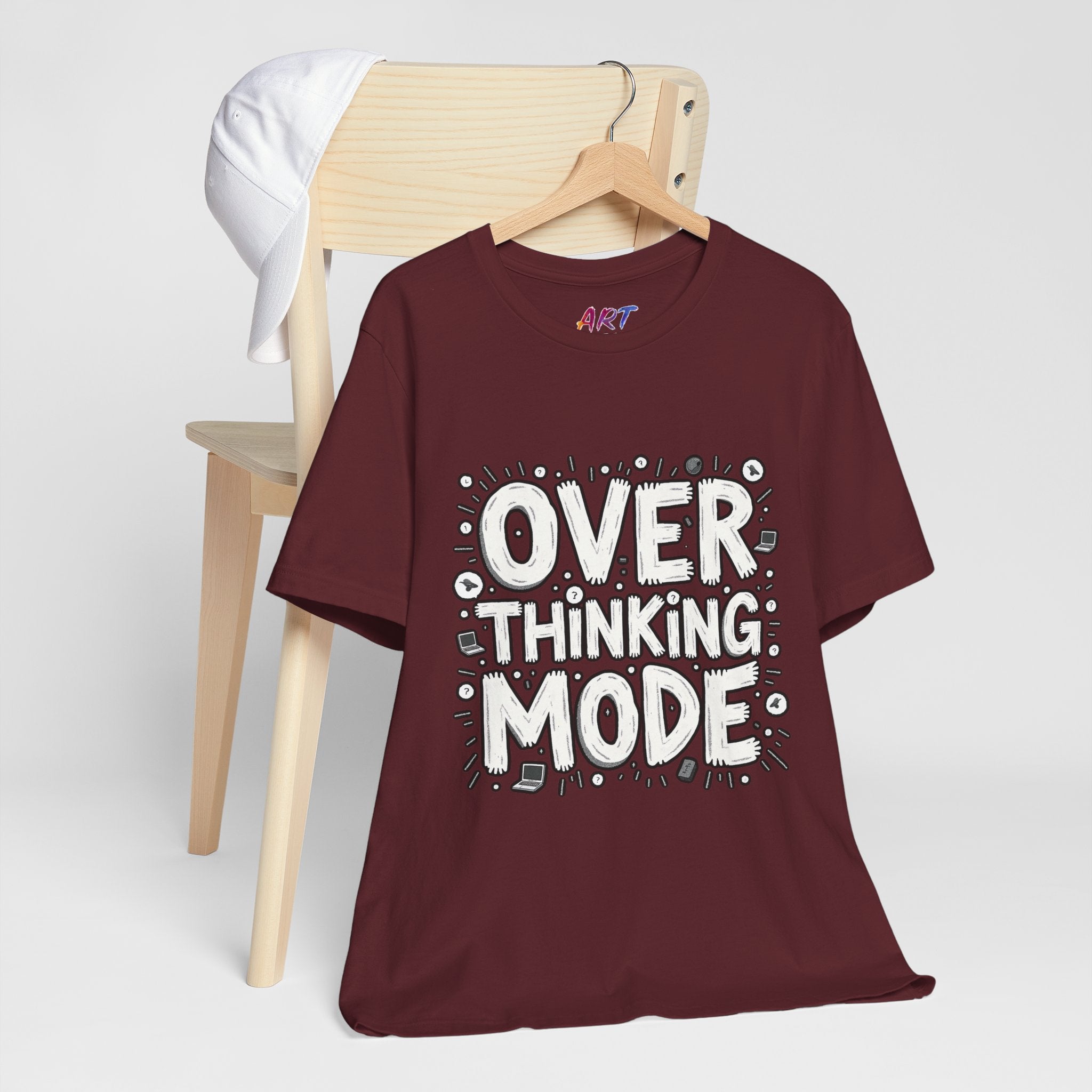 White hand-drawn typography saying Overthinking Mode with laptop and book doodles on a dark premium t-shirt.